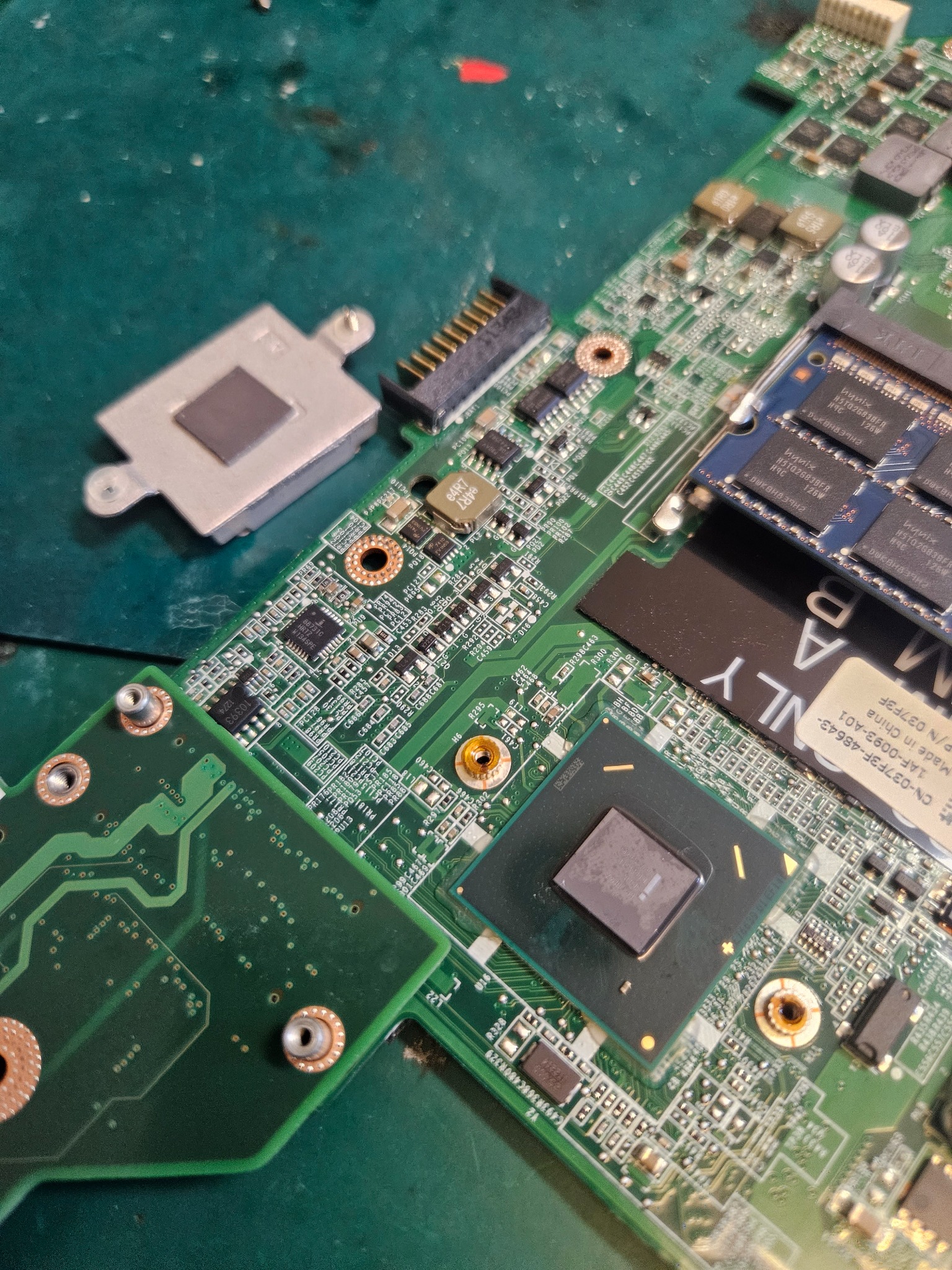 Szczegółowe zbliżenie na płytę główną laptopa z widocznym procesorem, pamięcią RAM Hynix i innymi elementami elektronicznymi, ukazujące skomplikowaną strukturę i miniaturyzację podzespołów.