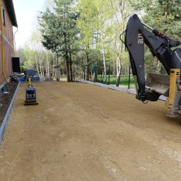 Jaworex - Przygotowanie podłoża pod nawierzchnię z użyciem zagęszczarki i koparko-ładowarki Volvo BL71, widoczne obrzeża betonowe i podsypka piaskowa