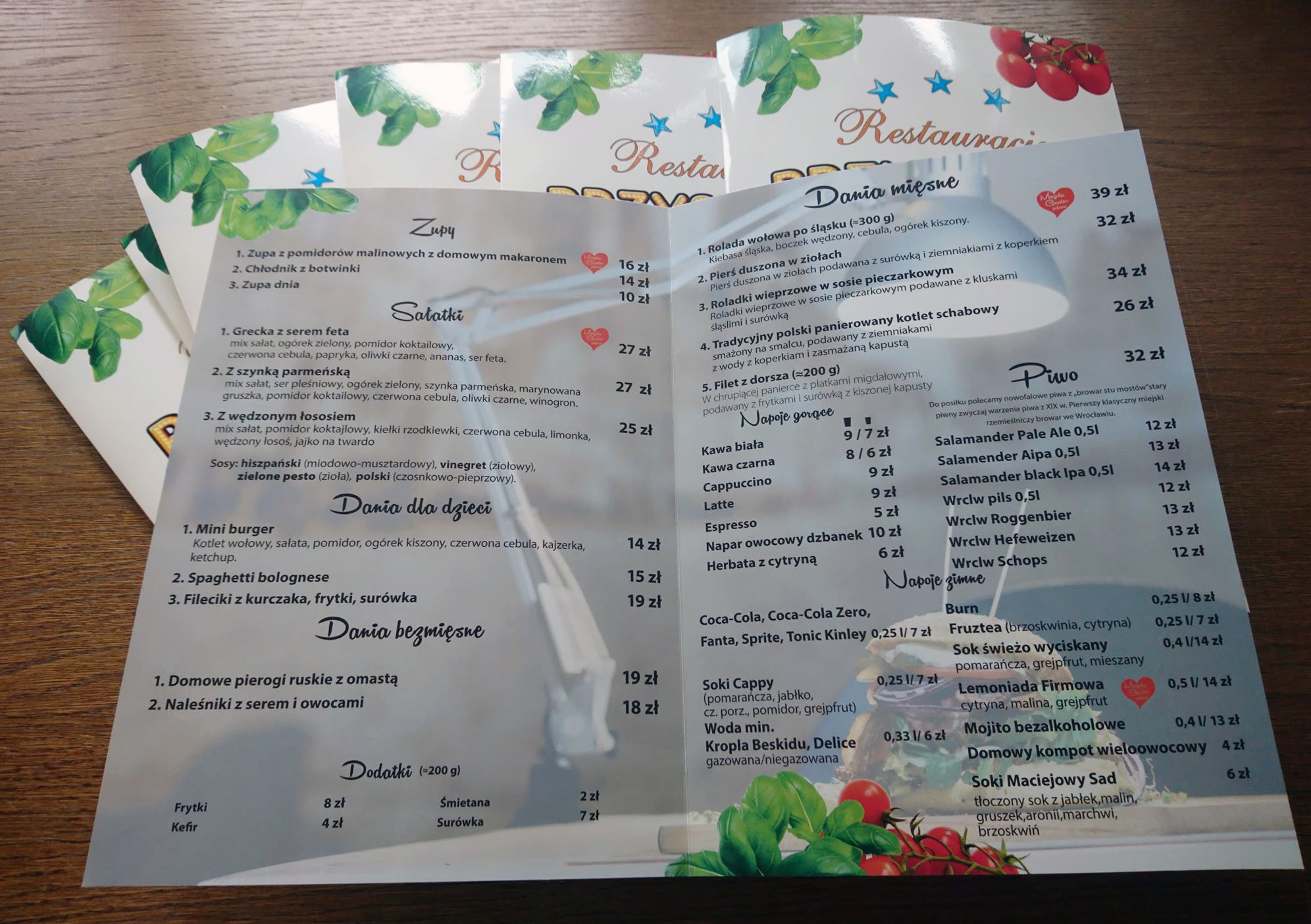 Menu restauracji z ofertą dań mięsnych, zup, sałatek, dań dla dzieci, dań bezmięsnych, napojów gorących i zimnych oraz piwa, z widocznymi cenami.