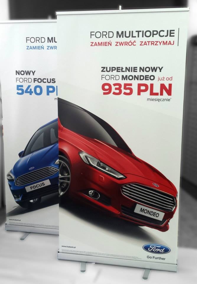 Dwa roll-upy reklamowe z ofertą samochodów Ford Focus i Mondeo, z widocznymi cenami i hasłami promocyjnymi na białym tle.