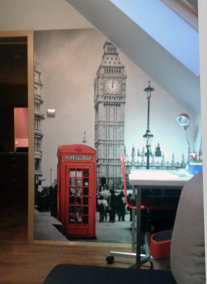 Tapeta przedstawiająca czarno-biały widok Londynu z czerwoną budką telefoniczną, widoczna w pokoju z ukośnym sufitem.