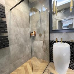 Z&M Kulakowski - Nowoczesna łazienka z kabiną prysznicową typu walk-in, grzejnikiem drabinkowym w kolorze czarnym, umywalką wolnostojącą i lustrem z dekoracyjnym oświetleniem.