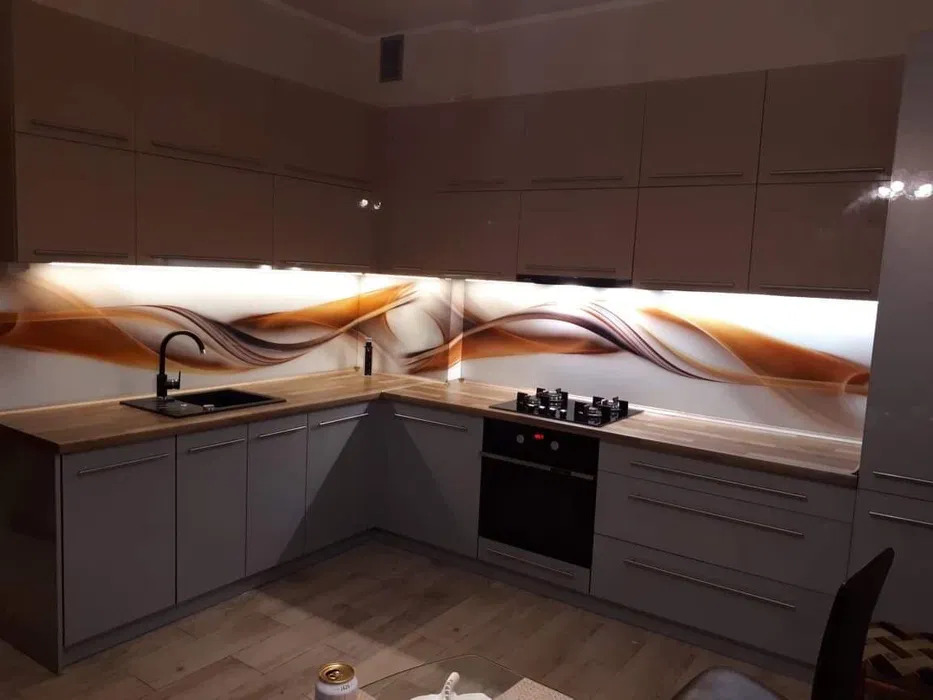 Szare szafki kuchenne z drewnianym blatem i podświetlanym panelem dekoracyjnym w brązowo-białe fale, czarny zlew i płyta grzewcza.