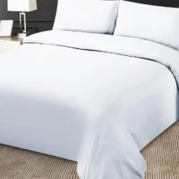 Świeżo pościelone łóżko z białą pościelą i dwiema poduszkami, widoczne elementy wystroju sypialni: lampka nocna i ramka na zdjęcia.