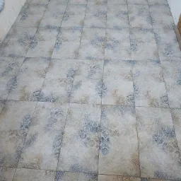 Ułożona podłoga z kwadratowych płytek ceramicznych w odcieniach beżu, brązu i granatu z dekoracyjnym, kwiatowym wzorem.