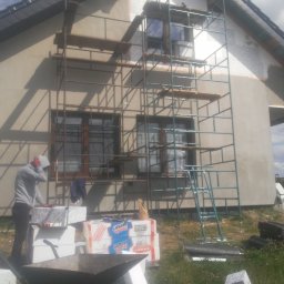 Edward Gryniewski - Prace przy ocieplaniu domu jednorodzinnego w Częstochowie, widoczne rusztowanie, styropian i pracownik przygotowujący materiał.
