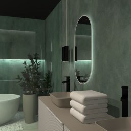 Flare Design Agata Mucha - Stylowa łazienka w odcieniach zieleni z owalnym lustrem z podświetleniem, minimalistyczną armaturą i rośliną doniczkową. W tle widoczna wanna na tle ściany z płytek.