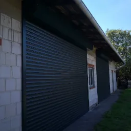 Zewnętrzny widok zamkniętej, ciemnej bramy rolowanej garażu z białej cegły w jasny dzień.