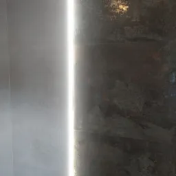 Ściana z płytek w odcieniach szarości i brązu, oświetlona pionową linią światła LED, tworząca nowoczesny efekt wizualny.