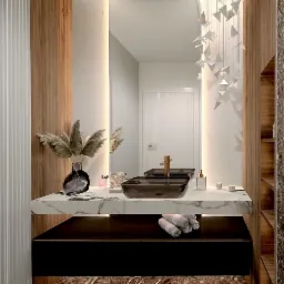 Elegancka łazienka z marmurowym blatem, umywalką z ciemnego szkła i złotą armaturą, oświetlona dekoracyjną lampą wiszącą i podświetleniem lustra.