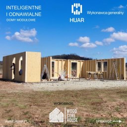 HUAR spółka z ograniczoną odpowiedzialnością - Wznoszenie konstrukcji domu modułowego z drewnianych paneli, widoczny pracownik wewnątrz, drabiny, wiązki kabli, stół roboczy, logo firmy HUAR i WOODBROS na tle błękitnego nieba.