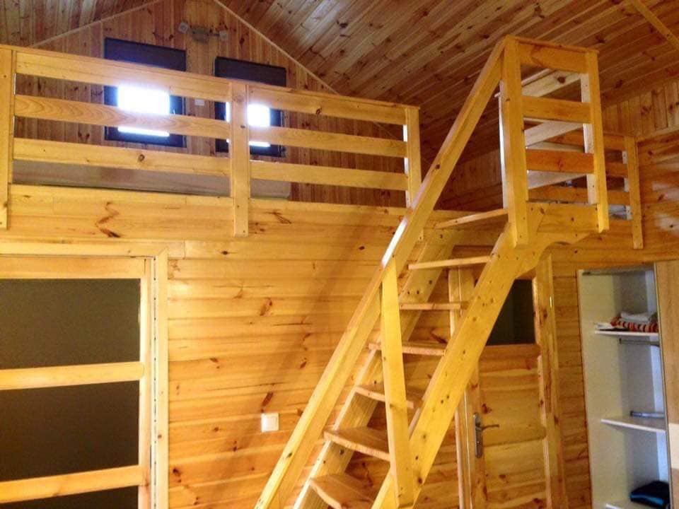 Wnętrze domu wykończone drewnem z antresolą, drewnianymi schodami i drzwiami.