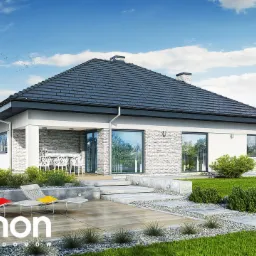 Wizualizacja parterowego domu jednorodzinnego z ciemną dachówką, jasną elewacją wykończoną kamieniem, tarasem z drewnianą podłogą i dwoma leżakami z kolorowymi poduszkami na tle zielonego ogrodu.