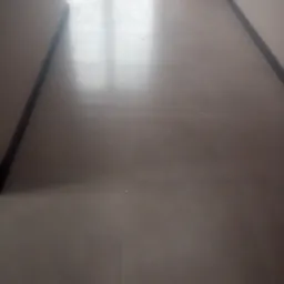 Błyszcząca, szara podłoga z płytek ceramicznych w korytarzu, widoczne listwy przypodłogowe w ciemnym kolorze i drzwi balkonowe w tle.