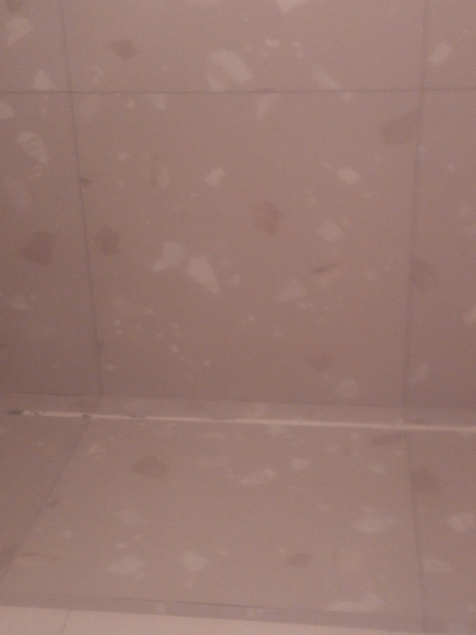 Beżowe płytki podłogowe i ścienne z delikatnym wzorem w łazience, widoczne fugi.