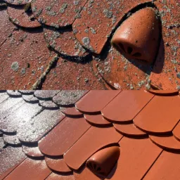 Częściowo wyczyszczony, czerwony dach z dachówki karpiówki z widocznymi elementami wentylacyjnymi; górna część dachu pokryta zabrudzeniami i mchem, dolna część po czyszczeniu, lśniąca w słońcu.