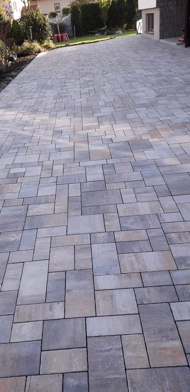 Nowa, ułożona zróżnicowana kostka brukowa w odcieniach szarości i beżu na podjeździe, widok z perspektywy