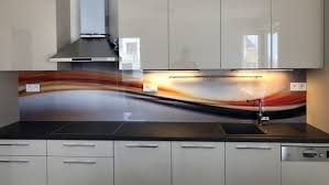 Szklany panel dekoracyjny z abstrakcyjnym motywem w odcieniach brązu, czerwieni i szarości zamontowany nad blatem kuchennym z czarnym zlewem i płytą indukcyjną, oświetlenie podszafkowe LED, białe...