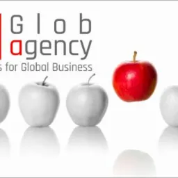 Logo Glob Agency z czerwonym jabłkiem wyróżniającym się na tle szarych, symbolizujące unikalne IT Services for Global Business na białym tle z odbiciem.