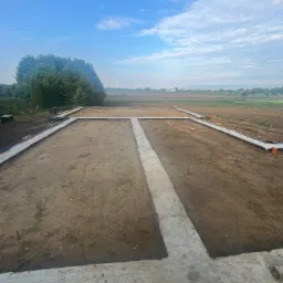 Fundamenty domu jednorodzinnego w Myślenicach, widziane z góry. Betonowe ławy fundamentowe, przygotowane do dalszych prac budowlanych, otoczone ziemią.