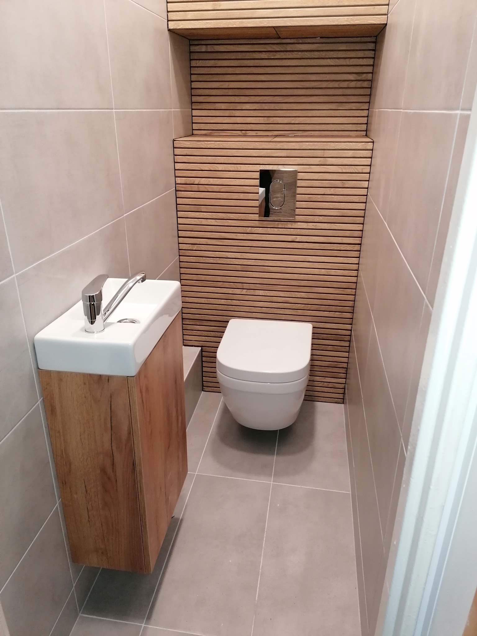 Nowoczesna toaleta z umywalką na drewnianej szafce i dekoracyjną ścianą z poziomych listew drewnianych.