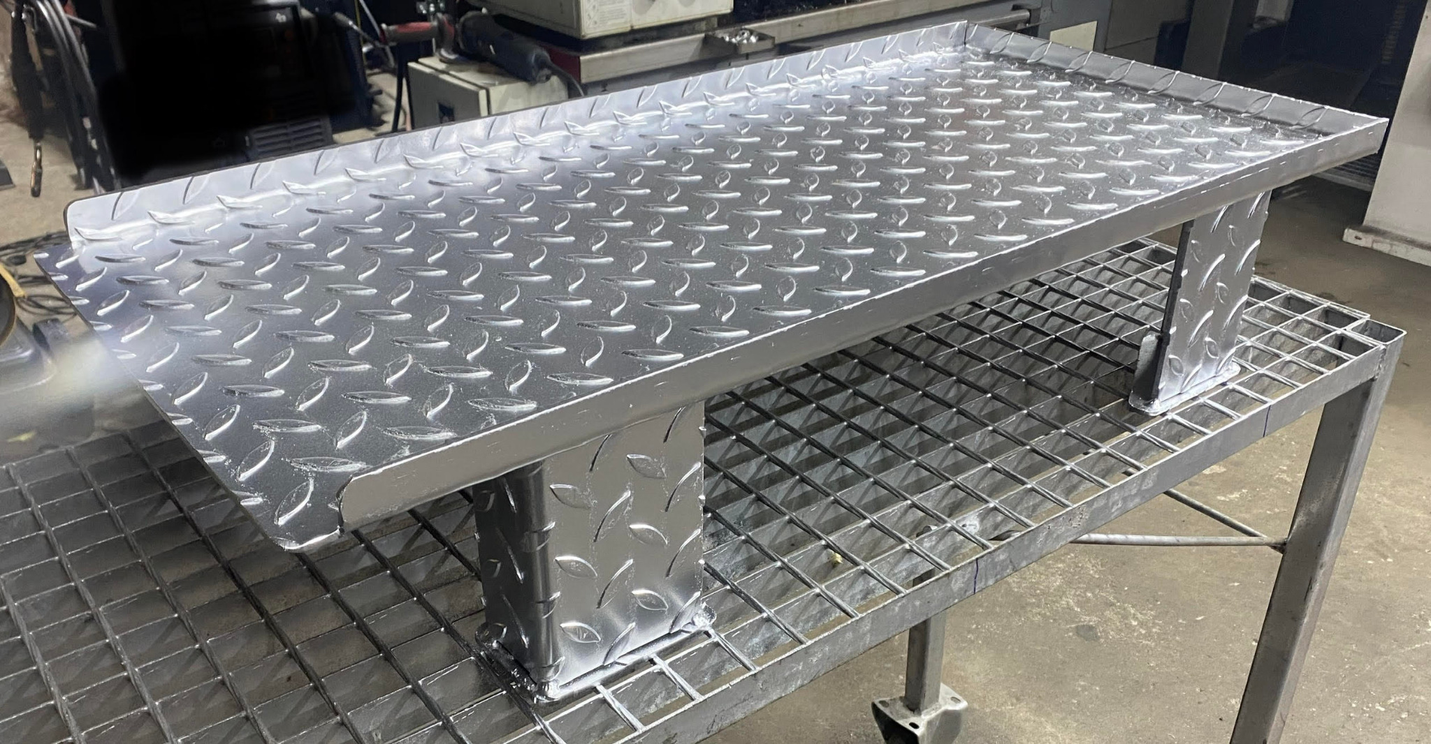 Stalowy stół roboczy z blachy ryflowanej, spawany na konstrukcji kratowej, widoczne ślady obróbki.