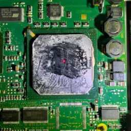 Zielona płyta główna komputera z wyraźnie widocznym procesorem pokrytym zaschniętą pastą termoprzewodzącą i śladami czyszczenia, wskazującymi na prace serwisowe.