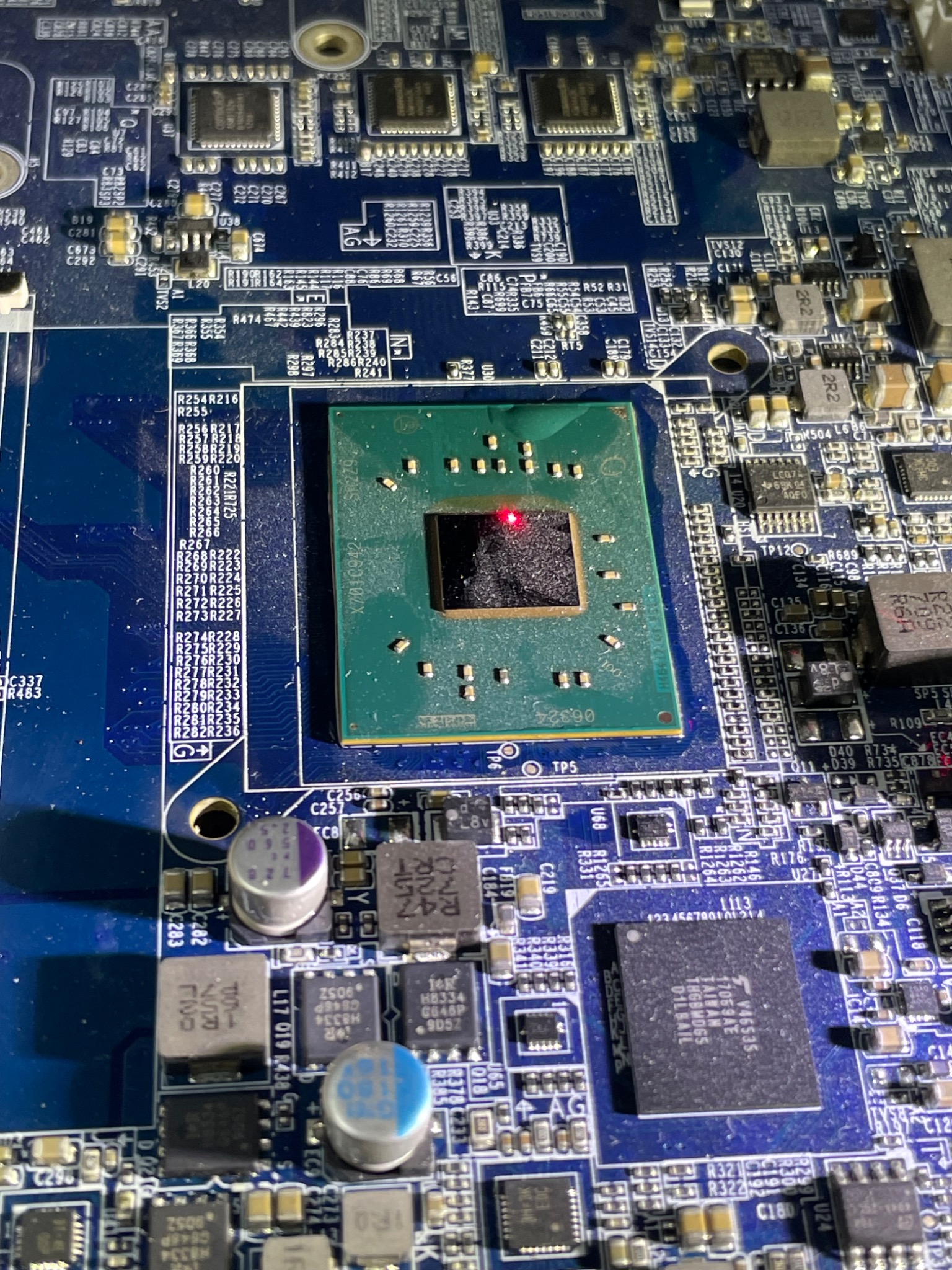 Zbliżenie na płytę główną komputera z widocznym procesorem, elementami elektronicznymi i oznaczeniami na laminacie.