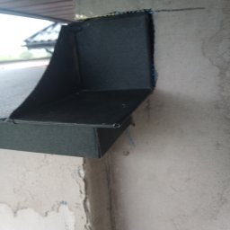 Dominik - Zamontowana, czarna obróbka blacharska przy krawędzi dachu, widoczna na tle surowego, szarego betonu.