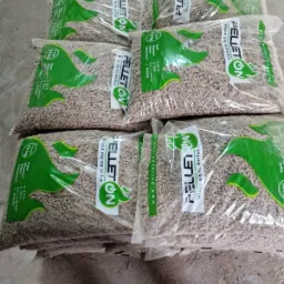 Ułożone worki z pelletem drzewnym, widoczne granulki przez przezroczyste opakowanie, etykieta z logo i specyfikacją produktu.