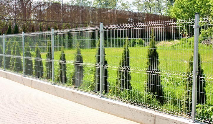 Panelowe ogrodzenie z siatki, zamontowane na betonowej podmurówce w Bojszowie. W tle zielony trawnik i tuje.