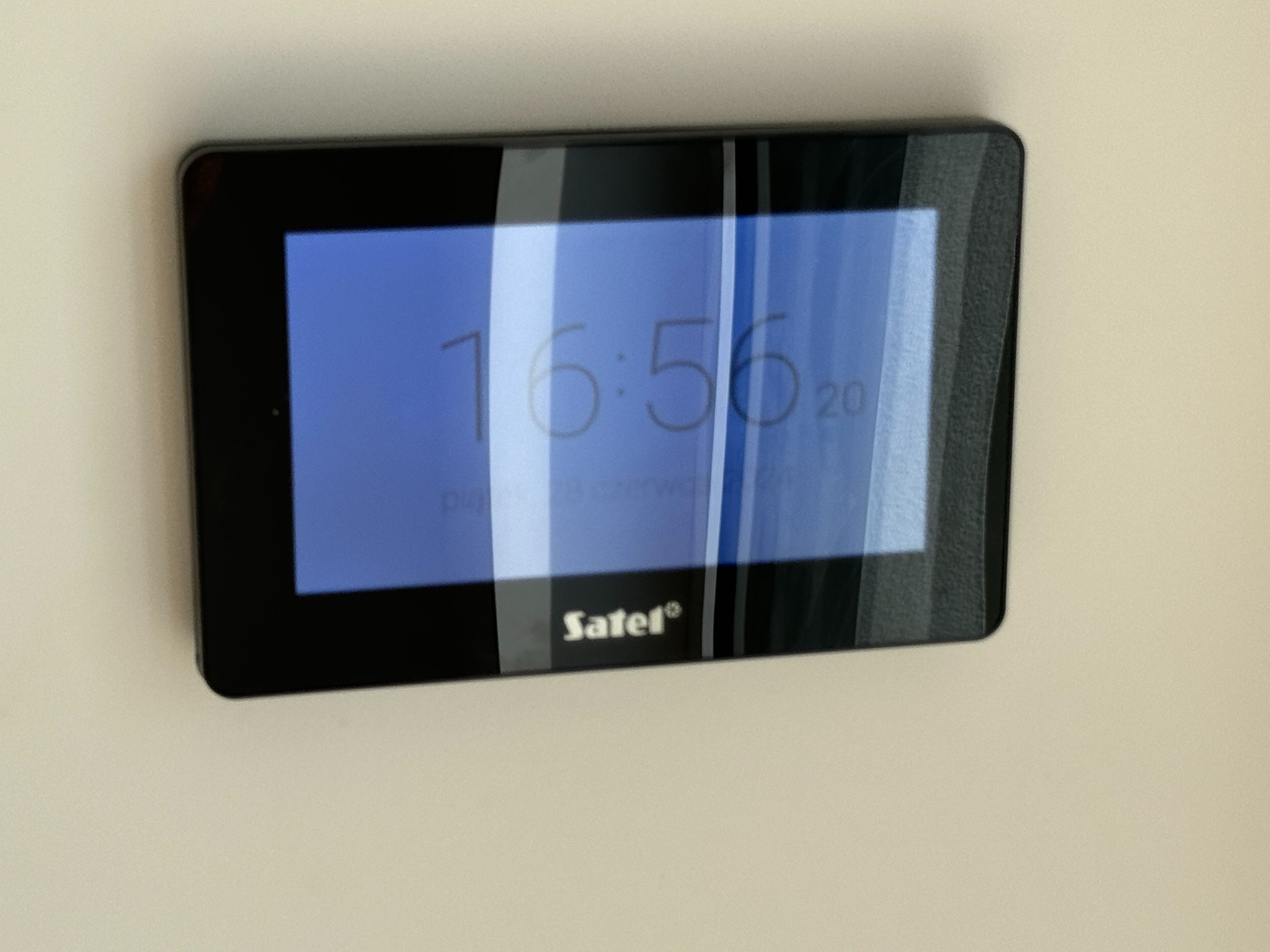 Panel sterowania systemu alarmowego Satel zamontowany na ścianie, wyświetlający aktualny czas i datę.