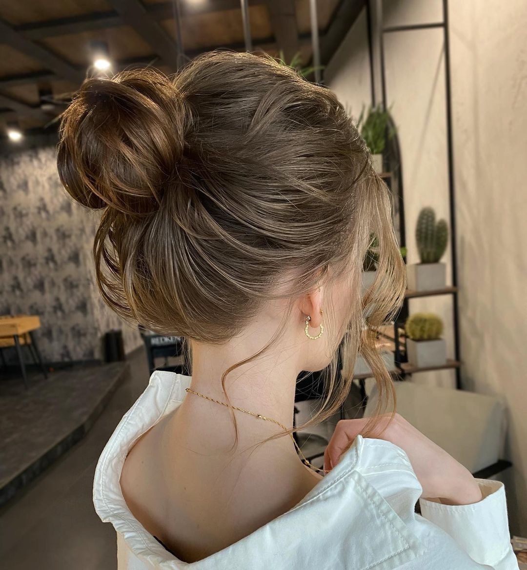 Eleganckie upięcie włosów w kok na głowie kobiety, widok z tyłu, złota biżuteria, fryzura wykonana w salonie fryzjerskim w Białymstoku.