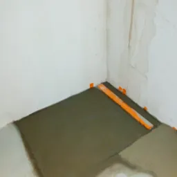 Wylewka samopoziomująca w rogu łazienki, z widocznymi pomarańczowymi elementami poziomującymi, przygotowana pod dalsze prace remontowe.