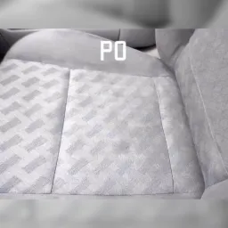 Szare, tekstylne obicie fotela samochodowego z geometrycznym wzorem w romby. Widoczne ślady użytkowania.