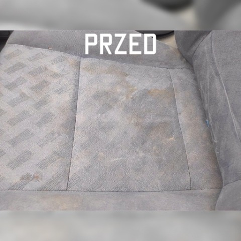 Brudne, szare siedzenie samochodowe z plamami i napisem 'PRZED' w górnej części zdjęcia.