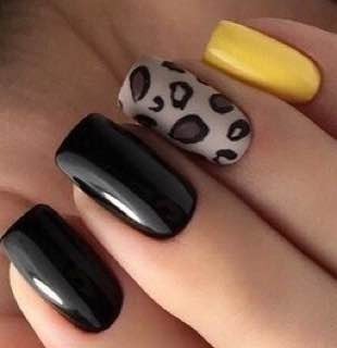 Kwadratowe paznokcie: dwa czarne, jeden z panterką na beżowym tle, jeden żółty. Ujęcie z bliska na palce dłoni.