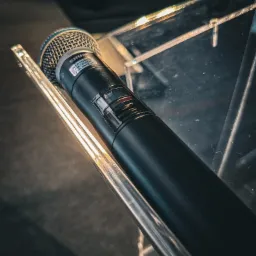 Wysokiej klasy cyfrowy mikrofon bezprzewodowy na mównicy z transparentnego plexi podczas konferencji.