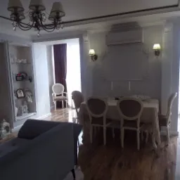 Eleganckie wnętrze salonu z parkietem, klasycznymi meblami, dekoracyjnymi listwami ściennymi i oświetleniem punktowym.