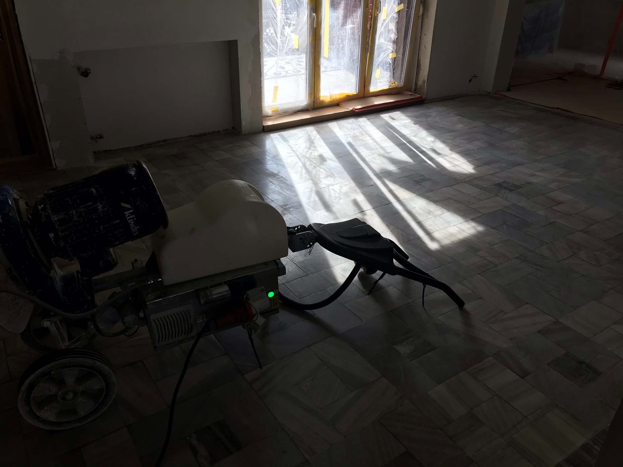 Maszyna do renowacji marmurowej posadzki w trakcie pracy w Kaliszu, widoczne promienie słoneczne wpadające przez okno, podkreślające wzór kamienia.