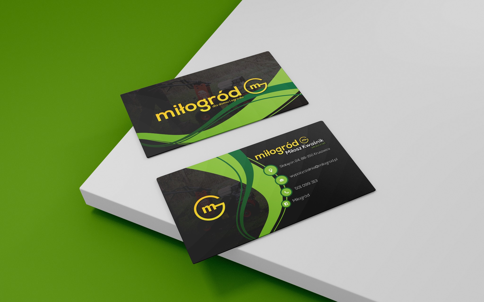 Dwie wizytówki firmy ogrodniczej 'miłogród' na białym podeście, z logo i danymi kontaktowymi, w kolorystyce czarno-zielono-żółtej, z motywem graficznym maszyny ogrodniczej w tle.