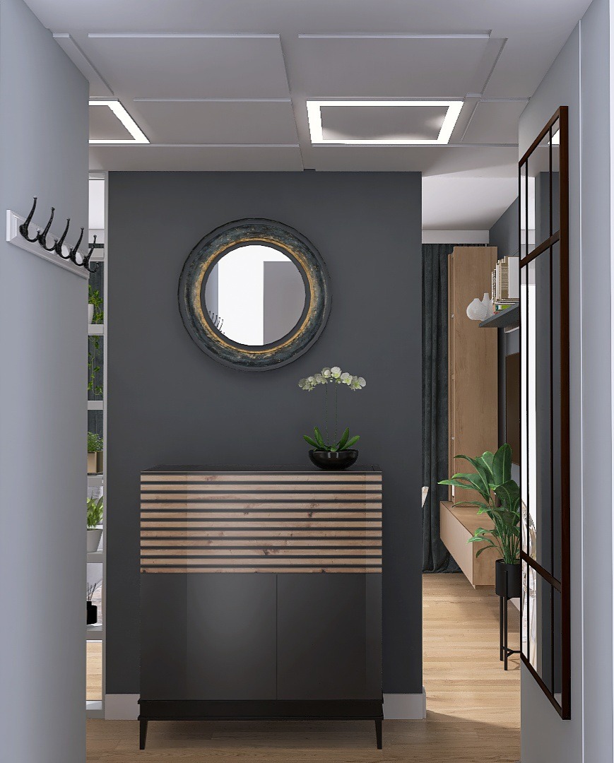 Wnętrze przedpokoju w odcieniach szarości z okrągłym lustrem w ozdobnej ramie, komodą z drewnianymi akcentami i storczykiem w czarnej doniczce, widok z perspektywy wejścia.