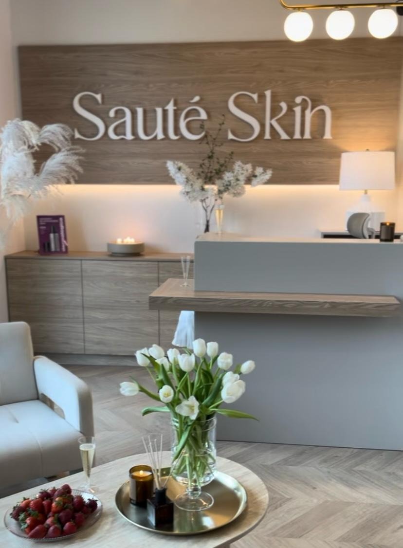 Nowoczesna zabudowa meblowa z drewnianym blatem i podświetleniem LED w salonie kosmetycznym, z dekoracjami kwiatowymi i owocami na stole.