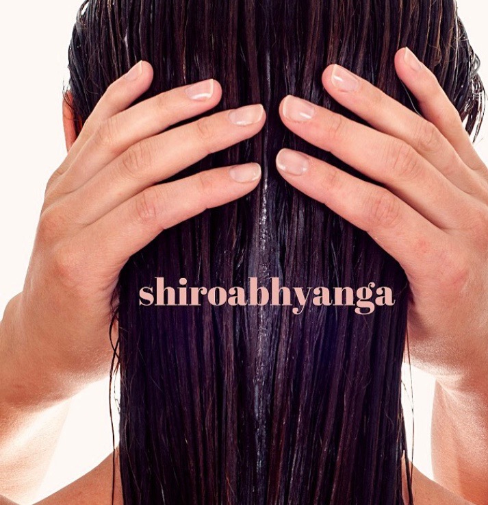 Widok z tyłu: dłonie na mokrych, ciemnych włosach tuż po zabiegu pielęgnacyjnym, z widocznym tekstem 'shiroabhyanga'.