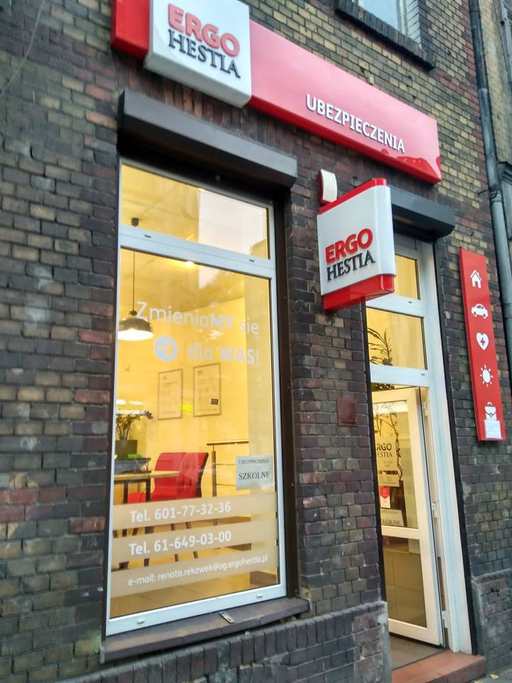 Fasada biura Ergo Hestia z szyldami reklamowymi, widoczne numery telefonów i adres e-mail na witrynie, budynek z cegły.