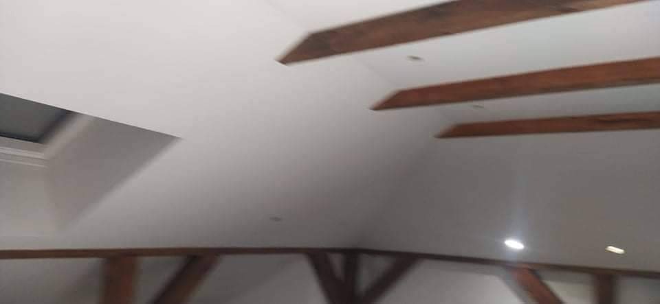 Poddasze w Piasecznie po ociepleniu, widoczne drewniane belki stropowe i okno dachowe, ściany wykończone na biało.