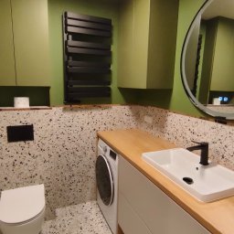 LEM-ART Remonty i Wykończenia Wnętrz Piotr Lemański - Nowoczesna łazienka w odcieniach zieleni z płytkami lastryko, czarnym grzejnikiem i okrągłym lustrem z podświetleniem LED. Umywalka nablatowa na szafce z drewnianym blatem.