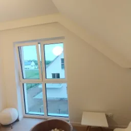 Poddasze po adaptacji na pokój dziecięcy z basenem z kulkami, stolikiem i krzesełkami, widok przez okno na dom sąsiada.