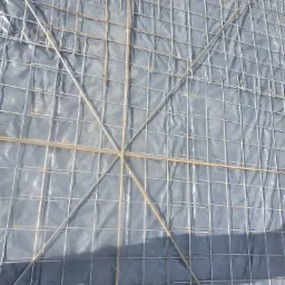 Zbrojenie stalowe ułożone na czarnej folii, przygotowane do zalania betonem pod fundament.