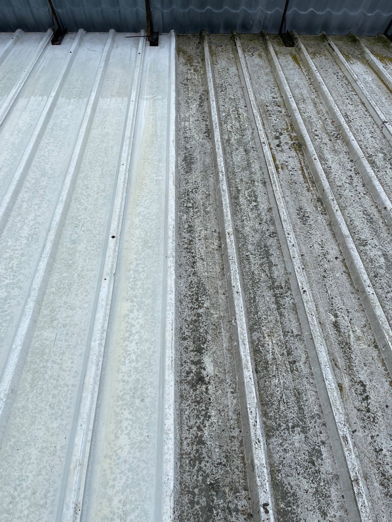 Częściowo wyczyszczony, blaszany dach z widoczną różnicą między umytą i brudną powierzchnią, ukazujący skuteczność czyszczenia.